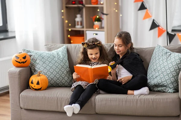 Meninas em trajes de Halloween ler livro em casa — Fotografia de Stock