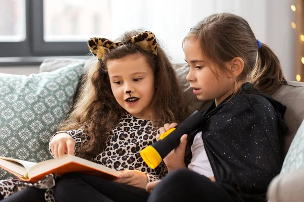 Девушки в костюмах на Хэллоуин читают книги дома — стоковое фото