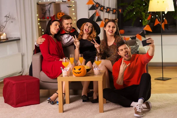 Glada vänner i halloween kostymer tar selfie — Stockfoto