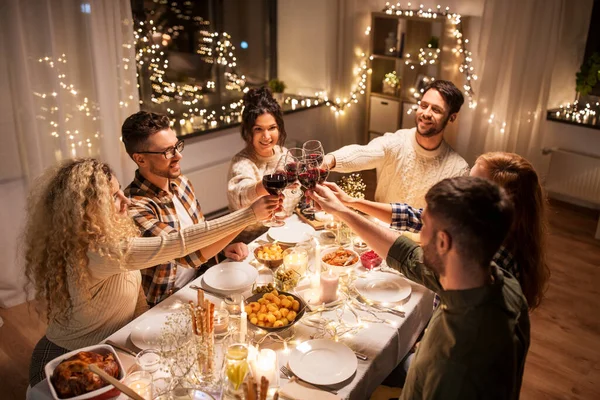 Amigos felizes bebendo vinho tinto na festa de Natal — Fotografia de Stock