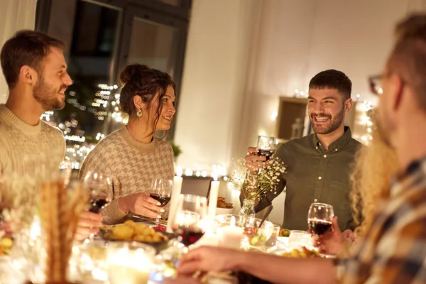 Amigos felices bebiendo vino tinto en la fiesta de Navidad —  Fotos de Stock