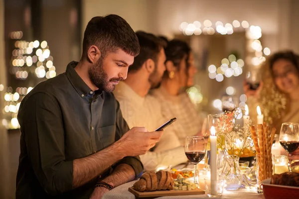 Мужчина со смартфоном на званом ужине с друзьями — стоковое фото