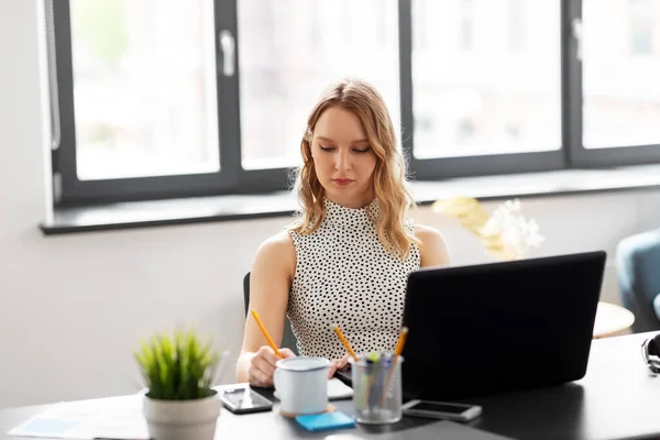 Forretningskvinne som skriver til en notatbok på kontoret – stockfoto