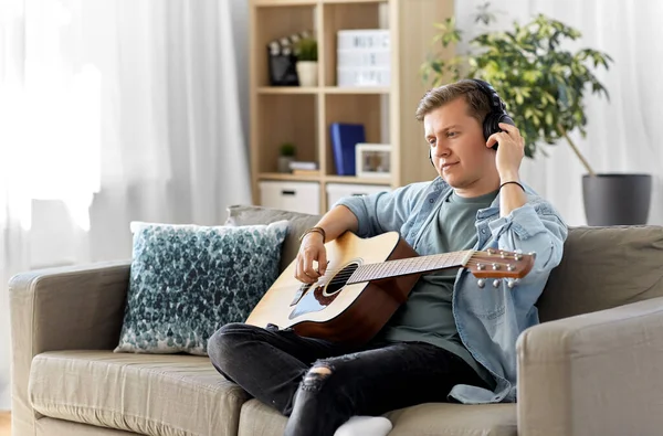 Hombre en auriculares tocando la guitarra en casa — Foto de Stock