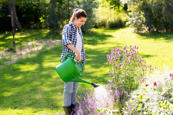 Jonge vrouw water geven bloemen in de tuin — Stockfoto