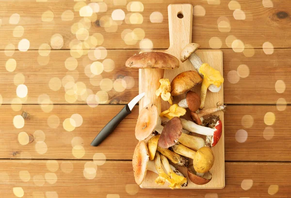 Eetbare paddenstoelen op houten snijplank en mes — Stockfoto