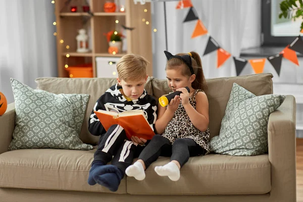 Barn i halloween kostymer läsa bok hemma — Stockfoto