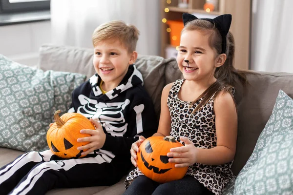 Crianças em trajes de Halloween com abóboras em casa — Fotografia de Stock