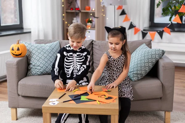 Дети в костюмах на Хэллоуин делают поделки дома — стоковое фото