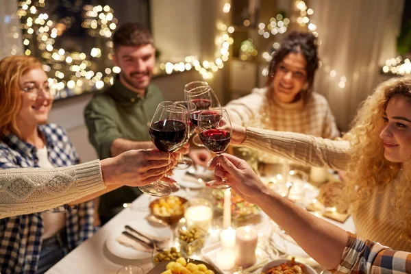 Glada vänner dricker rött vin på julfesten — Stockfoto
