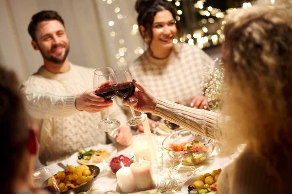 Amigos felices bebiendo vino tinto en la fiesta de Navidad — Foto de Stock