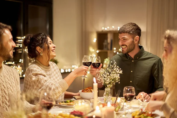 Glückliche Freunde, die auf der Weihnachtsfeier Rotwein trinken — Stockfoto