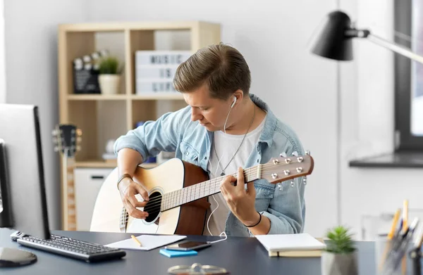 Hombre con auriculares y smartphone tocando la guitarra —  Fotos de Stock