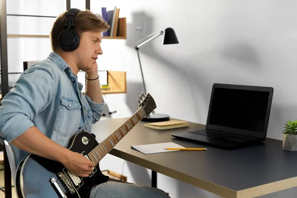 Man in headphones playing bass guitar at home — Stock Photo, Image