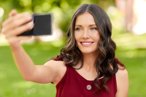 Mulher feliz com smartphone tirando selfie no parque — Fotografia de Stock