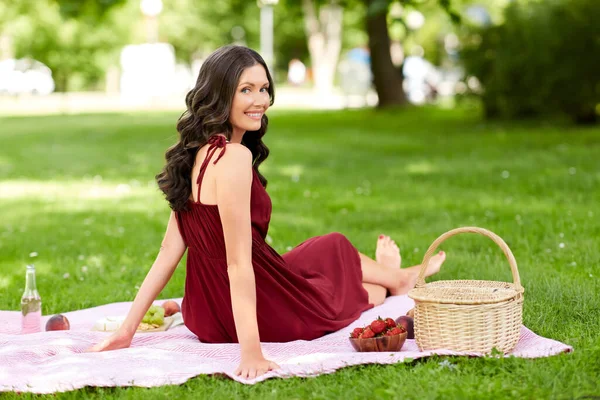 Gelukkig vrouw met picknick mand in zomer park — Stockfoto