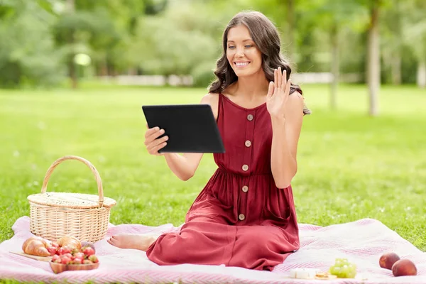 Mujer con tablet pc teniendo videollamada en el picnic —  Fotos de Stock