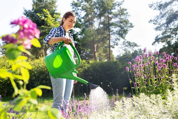 Jonge vrouw water geven bloemen in de tuin — Stockfoto