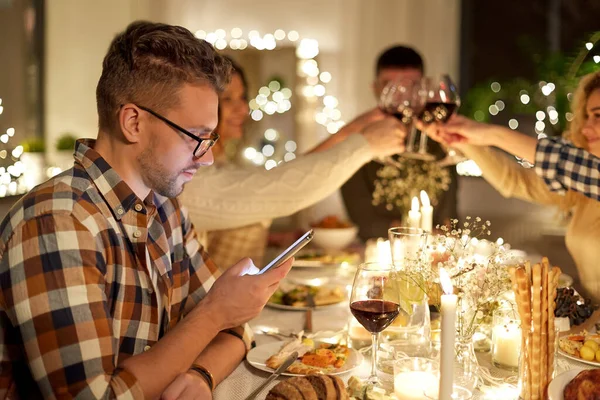 Uomo con smartphone a cena con gli amici Fotografia Stock