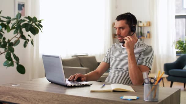Man met headset en laptop thuis aan het werk — Stockvideo