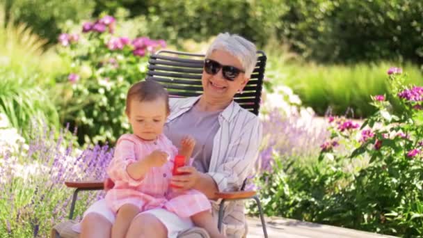 Glückliche Oma und kleine Enkelin im Garten — Stockvideo