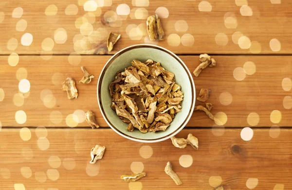 Dried mushrooms in bowl on wooden background — Stock Photo, Image