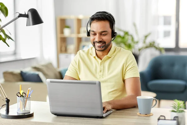 Uomo indiano con auricolare e laptop che lavora a casa — Foto Stock