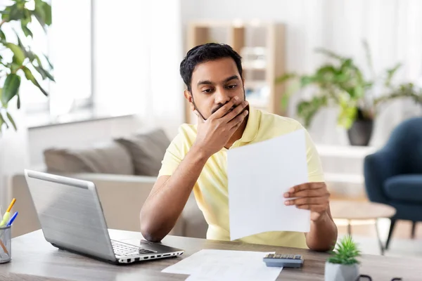 Homme avec calculatrice et papiers travaillant à la maison — Photo