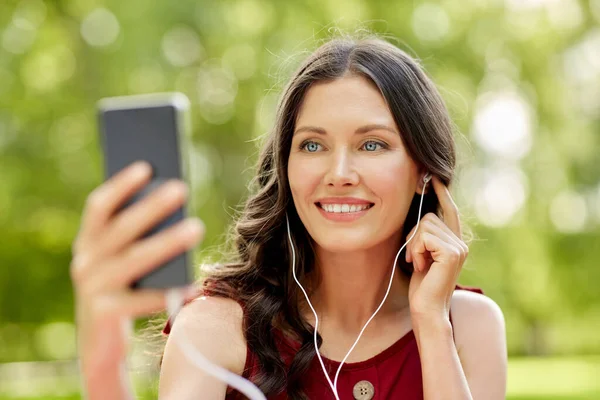 Parkta akıllı telefonu ve kulaklığı olan bir kadın. — Stok fotoğraf