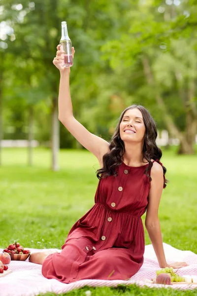 Glad kvinna rostning dryck på picknick i parken Stockbild