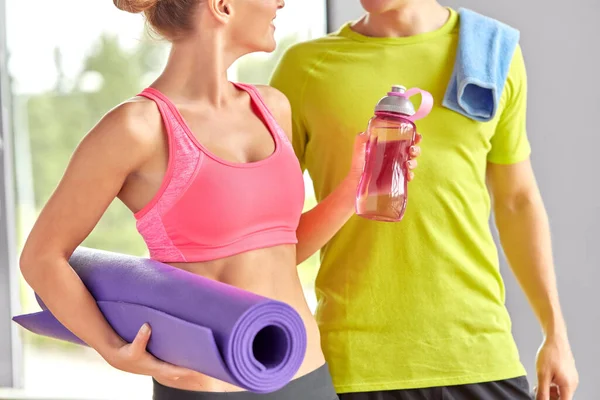 Paar mit Wasserflasche, Matte und Handtuch im Fitnessraum — Stockfoto