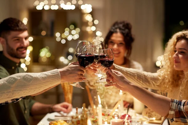 Amigos felices bebiendo vino tinto en la fiesta de Navidad —  Fotos de Stock