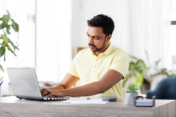 Hombre con laptop y papeles trabajando en casa —  Fotos de Stock