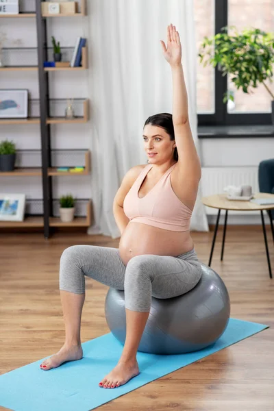 Mujer embarazada haciendo ejercicio en la pelota de fitness en casa — Foto de Stock