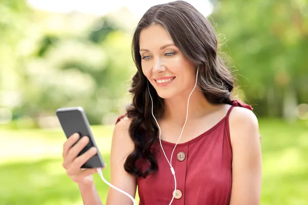 Vrouw met smartphone en oortjes in het park — Stockfoto