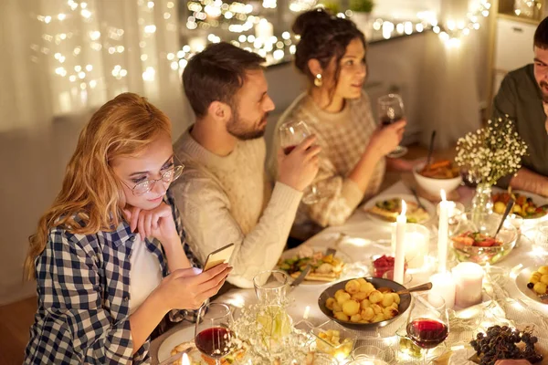 友達と食事会でスマートフォンを持つ女性 — ストック写真