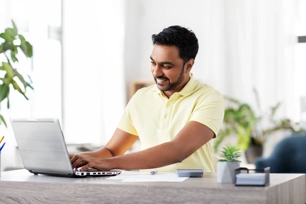 Hombre con laptop y papeles trabajando en casa —  Fotos de Stock