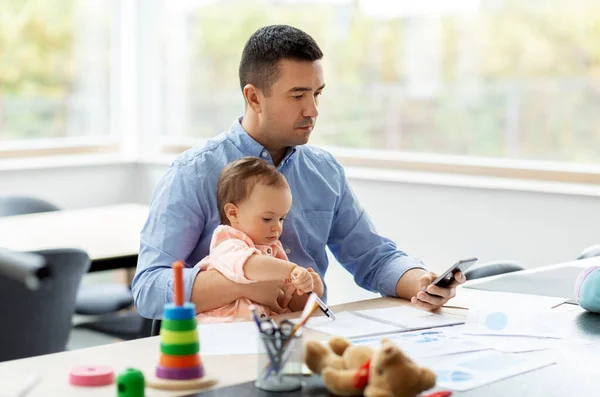Padre con bambino e smartphone che lavora a casa — Foto Stock