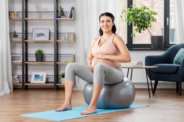 Mujer embarazada haciendo ejercicio en la pelota de fitness en casa —  Fotos de Stock