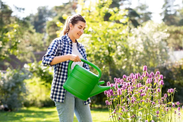 Jonge vrouw water geven bloemen in de tuin — Stockfoto