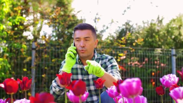 Μεσήλικας με smartphone στον κήπο με τα λουλούδια — Αρχείο Βίντεο