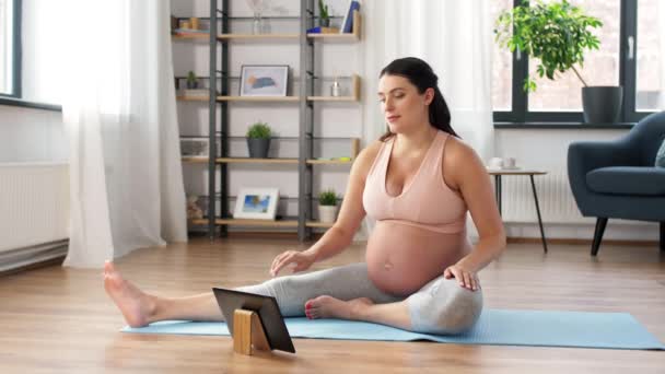 Gravid kvinne med nettbrett pc driver med sport hjemme – stockvideo