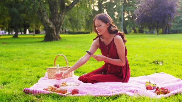 Mulher feliz com smartphone no piquenique no parque — Vídeo de Stock