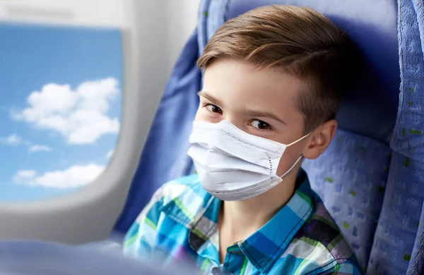 Chlapec v lékařské masce cestující letadlem — Stock fotografie