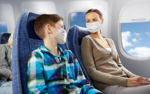 Mãe e filho em máscaras viajando de avião — Fotografia de Stock