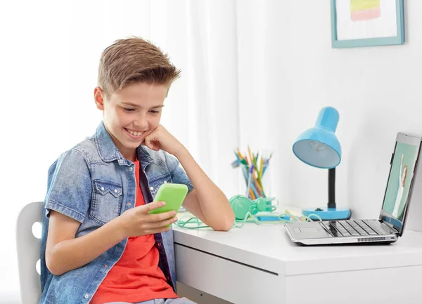 Niño feliz con teléfono inteligente y portátil en casa —  Fotos de Stock