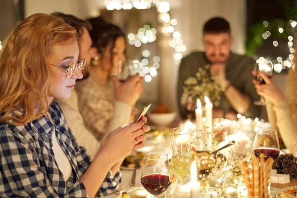 Vrouw met smartphone op diner feest met vrienden — Stockfoto