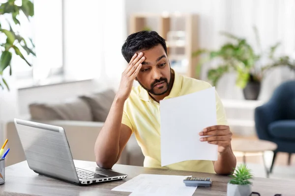 Homme avec calculatrice et papiers travaillant à la maison — Photo