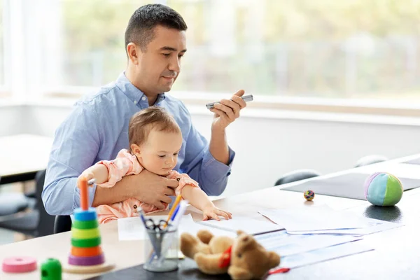 Padre con bambino e telefono che lavora a casa ufficio — Foto Stock