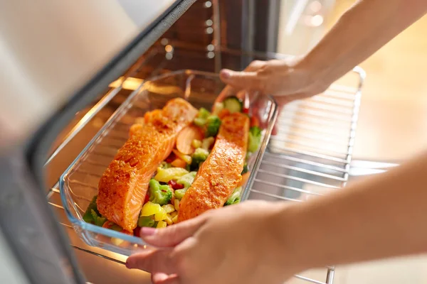 Kvinna matlagning mat i ugn hemma kök — Stockfoto